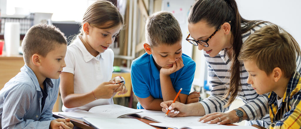 Lehrerin am Tisch mit Grundschulkindern